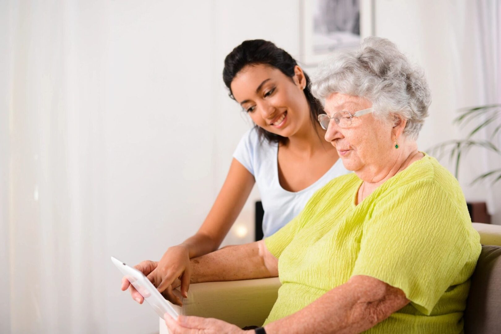 A girl with elderly woman playing with digital tablet